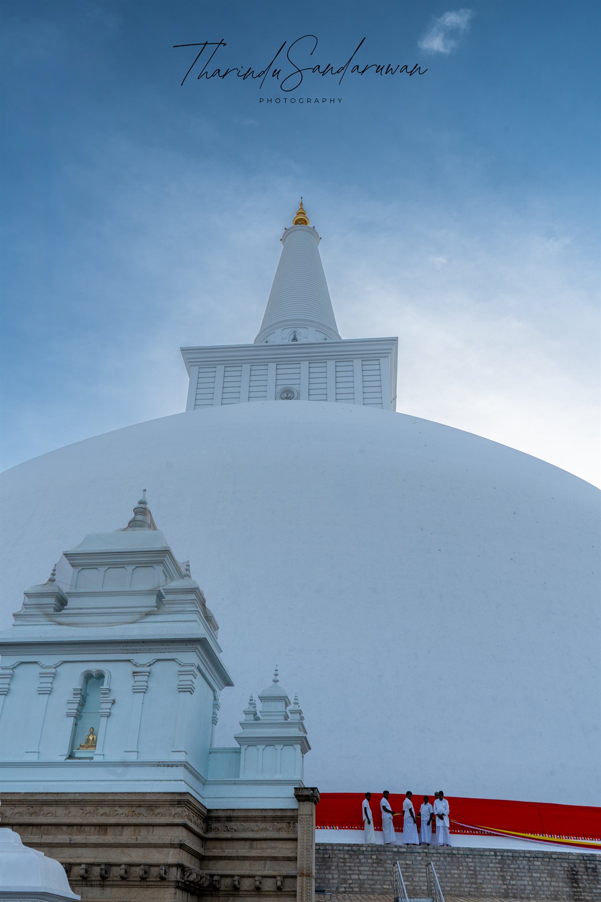 A towering white stupa and shrine beneath a clear blue sky.